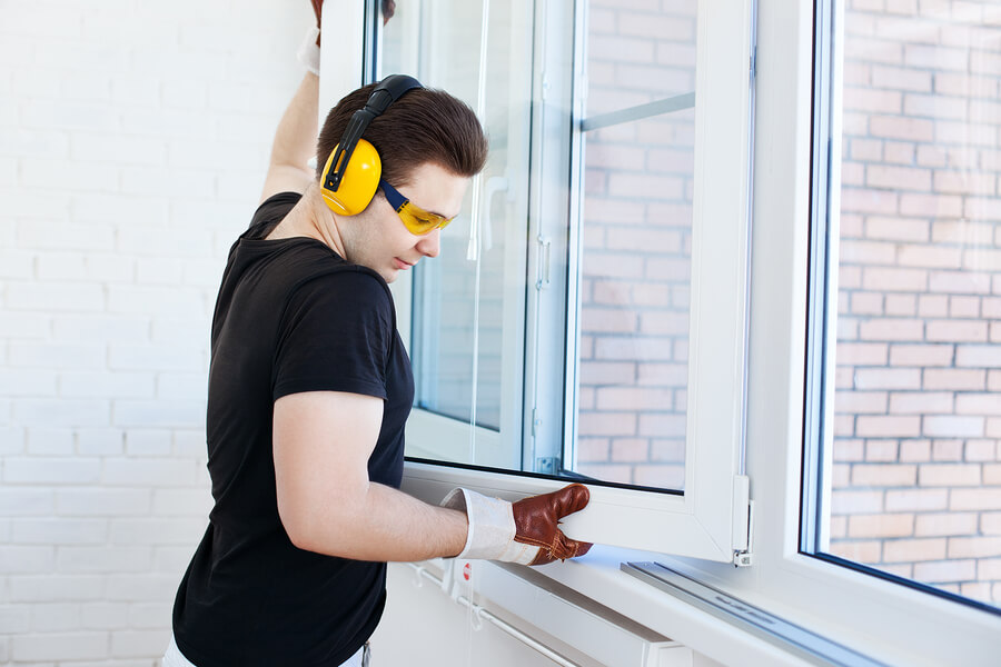 Male worker mounting a window on a balcony whilst wearing gloves