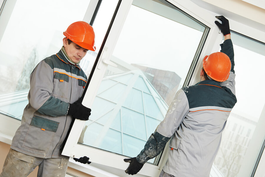 Two male commercial emergency glass repair workers installing a window