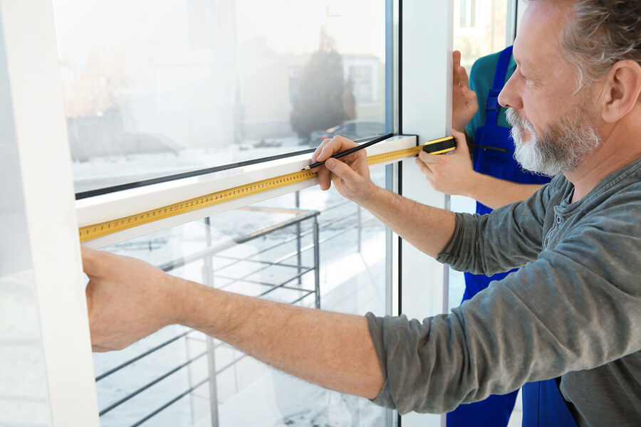 Senior worker measuring a windowed door for replacement